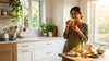 Woman drinking warm honey water with raw honey jar and lemon slices in kitchen to illustrate whether honey helps with weight loss